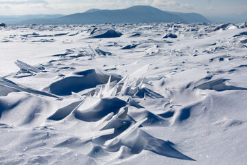 Fototapeta na wymiar Gremyachinsk, Baikal, Russia February 10, 2019. Texture ice landscape on winter snow-covered Baikal. Ice hummocks. The purest ice of Baikal.