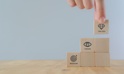 Mission vision values concept icon on wooden cubes stairs on beautiful grey background. Copy space....