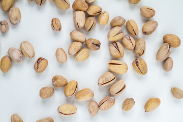 Pistachios (pistacia vera), unpeeled, in their hard shells. Nuts flat lay composition on a white background.
