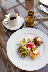 Tripoli, Lebanon, January 19, 2019, various traditional oriental sweets on a plate, Lebanese cuisine, a cup of coffee and a coffee turka (coffee pot). © Mikhail