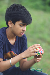 Indian boy try to complete the rubik's cube - technical and business solving problem and brain training concept