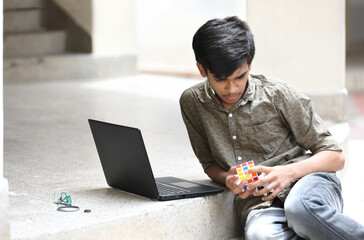 Indian boy try to complete the rubik's cube - technical and business solving problem and brain training concept