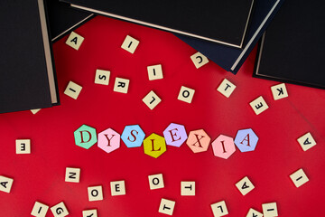 Hexagonal tiles  with letters spelling DYSLEXIA with plastic tiles and books. Dyslexia is a reading...