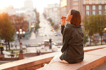 Woman at sunset with amazing city view, enjoying warm days, freedom, positive vibes, smoking ...