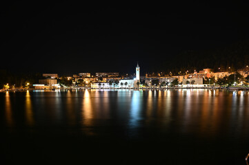 Fototapeta na wymiar City of Ploce and Adriatic sea in Croatia by night. Panoramic view of buildings in town reflected in the water. 