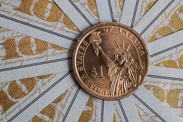 American one dollar coin with the image of the statue of liberty and the dollar symbol against the background of fragments of 100 dollar bills