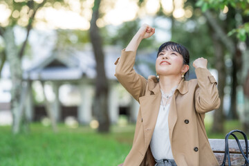 公園のベンチでガッツポーズする女性