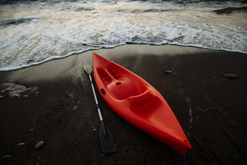 orange kayak with an oar by the sea