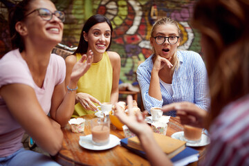 group of women surprised by the story of their female friend, sitting in the outdoor cafe