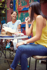 two female friends talking  in outdoor cafe, having a good time