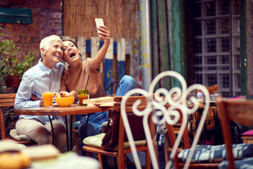 Obraz na płótnie Canvas mother and daughter concept. young adult caucasian female and elderly woman taking selfie with cell phone, smiling.