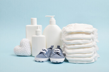 Various accessories for children's hygiene. A large stack of diapers next to them are bottles of baby cosmetics.