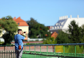 Fototapeta Młody mężczyzna robi zdjęcia telefonem komurkowym, smartfonem, ręka, Wrocław.
 obraz