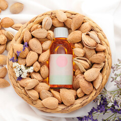 Bottled almond oil on a bowl full of almonds with flowers and white background