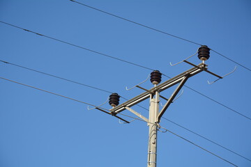 Low angle close-up view of the top part of an electricity distribution pylon and power lines under...