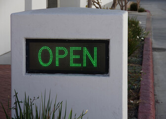 Obraz premium An outdoor sign saying OPEN in illuminated green LED letters on black ground