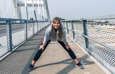 One young happy and self loved sporty jogger woman taking a short break for rest after jogging and running outdoor over the bridge for healthy life doing bodyweight workout and training