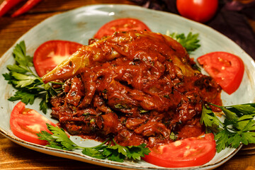 Closeup of armenian dish tjvjik or fried beef liver in plate with tomatoes and greens
