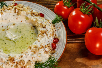 Closeup of creamy salad with nuts, garlic, cucumber and greens decorated with cherry tomatoes