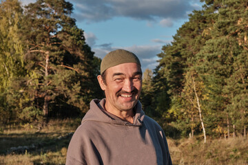 Portrait of senior Muslim asian man in skullcap and sweatshirt looking at camera and smiling