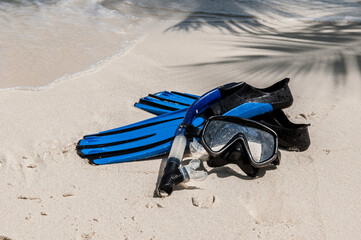 Mask and fins for scuba diving and snorkeling lie on the sandy shore against the backdrop of the...