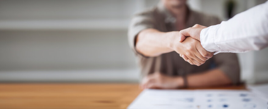 Close up of two businesspeople shaking hands after a deal contract is done.