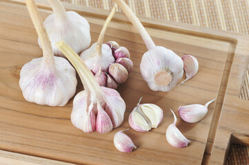 young garlic - whole garlic heads and slices on a wooden board