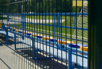 Metal tribune with seats in blue-yellow colors. Metel lattice as a weapon. The concept of a small tribune for fans. Selective focus.
