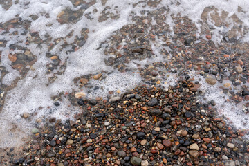 Water is washed up on a stony sandy beach, texture background wallpaper, stones and sand