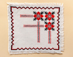 On a yellow background, a white napkin with embroidered ornaments with red and black threads. Handmade