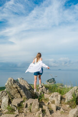 Obraz premium Girl in summer clothes on the top of the mountain near the sea