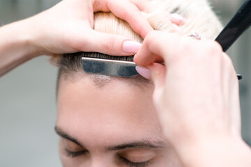 straight razor. haircut process of blond young man in barbershop salon