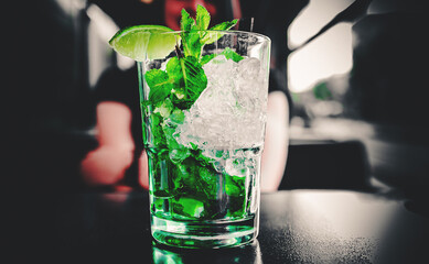 glass with mohito lemonade cocktail in cafe on table on dark background