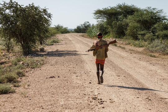 Omo Valley, Ethiopia. An unidentified man from the Hamer tribe with a gun walks along the road.