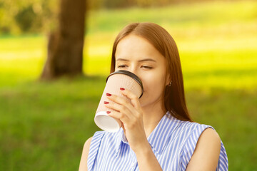coffee take away,young woman drinks a hot drink in the morning before working in park