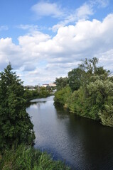 Fototapeta na wymiar River bend panorama. View of the river with overgrown banks. Beautiful clouds over the river.