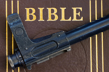 The automatic gun lying on the Bible, close up.