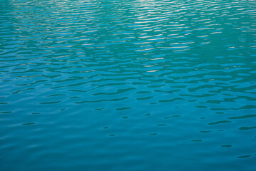 Turquoise water surface with light waves as a texture or background