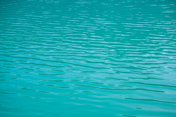 Turquoise water surface with light waves as a texture or background