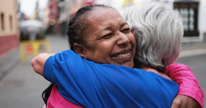 Senior multiracial women meeting and hugging each other in the city - Elderly people friendship love concept