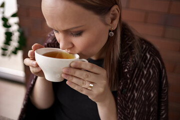 Close-up portrait of smiling woman drinking tea alone.
