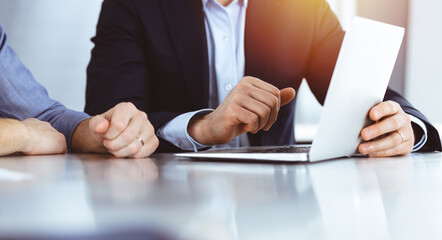 Business people using laptop computer while working together in sunny modern office. Unknown businessman with colleague at workplace. Teamwork and partnership concept