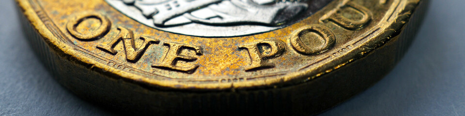 The British 1 pound sterling coin close-up. Banner or headline about economy, money or banking in...