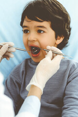 Little arab boy sitting at dental chair with open mouth during oral checking up with dentist doctor. Stomatology concept