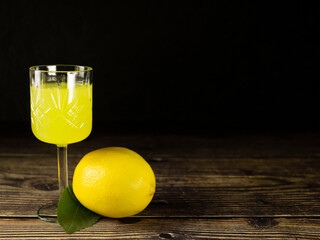 Limocello or poncha liqueur with copyspace. Italian liqueur in a textured glass shot on a wooden...