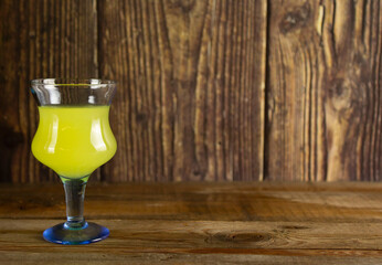 Limocello or poncha liqueur with copyspace. Italian liquor in a glass shot on wooden table and wooden background