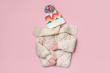 Kids warm puffer jacket with scarf  and hat on pink background. Stylish childrens outerwear. Winter...
