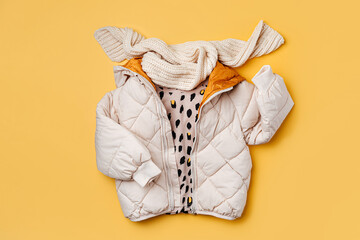 Kids warm puffer jacket with scarf on yellow  background. Stylish childrens outerwear. Winter fashion outfit © igishevamaria