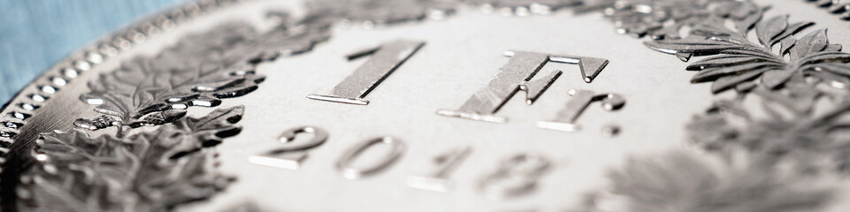 1 Swiss franc coin close-up. Banner on the topic of the economy, business, money of Switzerland. Light pale blue and brown headline. Banking and the national currency. Macro