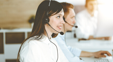 Asian woman working at customer service office. Business concept. Group of diverse operators at work in sunny call center.